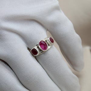 Pu&ograve; includere: Un anello d'argento con tre pietre ovali rosa incastonate in una fascia.