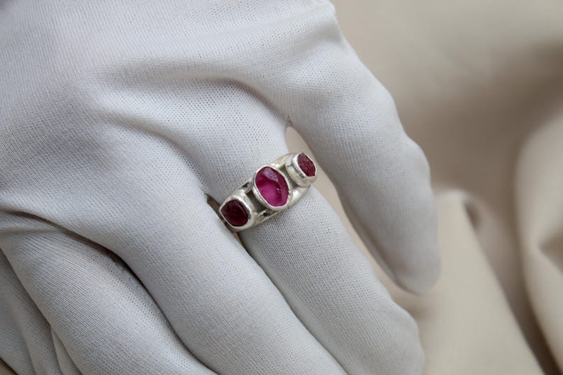 Pu&ograve; includere: Un anello d'argento con tre pietre ovali rosa incastonate in una fascia.