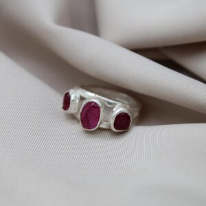Pu&ograve; includere: Un anello d'argento con tre pietre di rubino rosa incastonate nella fascia.