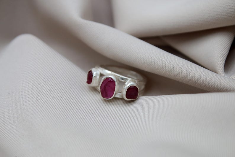 Pu&ograve; includere: Un anello d'argento con tre pietre di rubino rosa incastonate nella fascia.