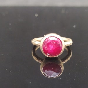 Pu&ograve; includere: Un anello d'oro con una pietra preziosa di rubino rosso brillante incastonata in una montatura a castone.