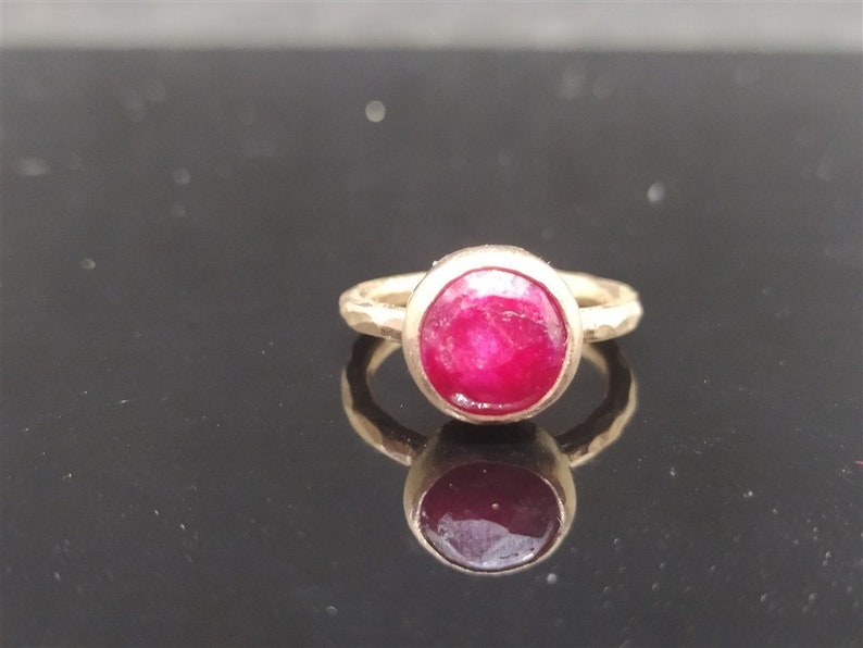 Pu&ograve; includere: Un anello d'oro con una pietra preziosa di rubino rosso brillante incastonata in una montatura a castone.