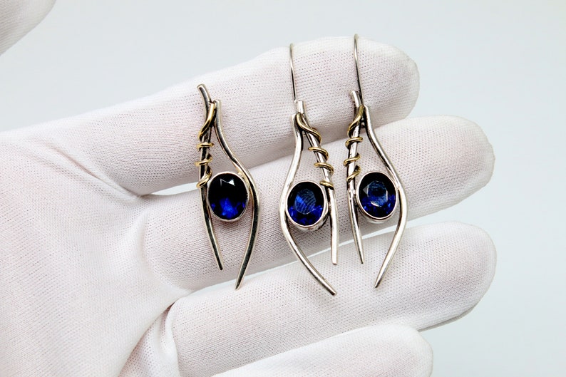 May include: A pair of silver dangle earrings with blue gemstone accents and gold wire accents.