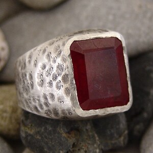 May include: A silver ring with a hammered texture and a large, rectangular, dark red gemstone.