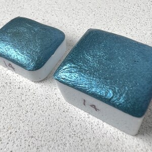 Puede incluir: Dos bandejas cuadradas de pintura acuarela met&aacute;lica azul verdoso. Las bandejas est&aacute;n etiquetadas con el n&uacute;mero "14".