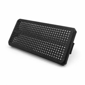 May include: A rectangular black pegboard panel featuring a uniform grid of small circular holes across its entire surface. The panel has a textured finish and a solid frame, designed with a mounting bracket visible on the right side edge.