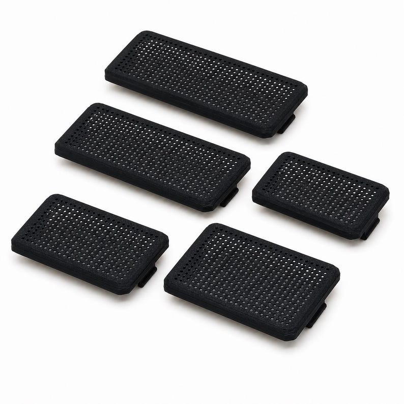 May include: A set of five rectangular black components featuring a uniform grid of small circular perforations across the top surface. Each piece has a slightly raised border and a small tab extending from one of the shorter sides of the base.