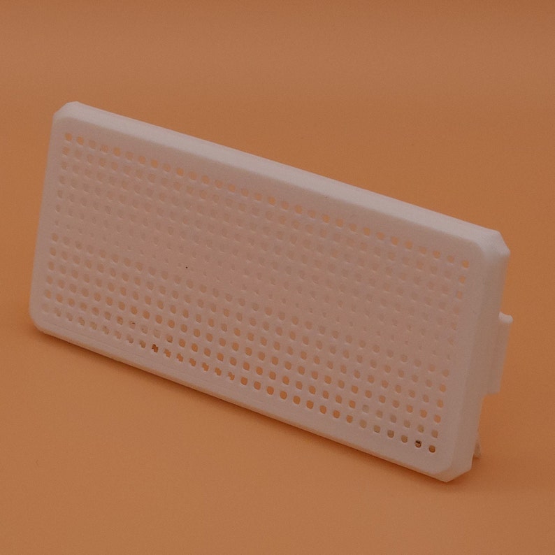 Puede incluir: Rejilla de ventilaci&oacute;n de pl&aacute;stico blanco con una cuadr&iacute;cula de peque&ntilde;os agujeros.