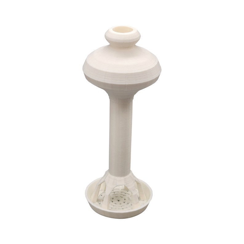 Puede incluir: Modelo de torre de agua de cer&aacute;mica blanca con una base redonda y una columna alta y delgada. La torre tiene una parte superior abovedada con una peque&ntilde;a abertura.