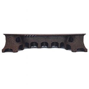 May include: A dark brown wooden bridge-shaped rack with arched openings. The rack has a textured surface and is designed to hold multiple items. The ends of the rack have a decorative flared design.
