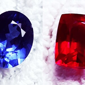 May include: Two faceted gemstones, one blue and one red, on a white background.