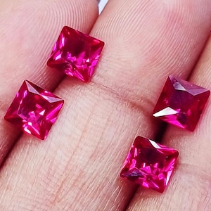 May include: Four square-cut, vibrant pink gemstones. Each gem has a faceted surface, catching the light and displaying a brilliant shine. The gems are a deep, saturated pink, with sharp edges and a symmetrical shape. These gemstones are ideal for jewelry making.