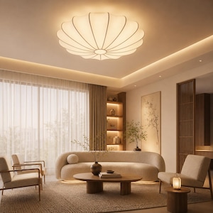 Può includere: Una lampada da soffitto bianca, circolare e plissettata con un'illuminazione morbida e luminosa. La lampada presenta un design segmentato a forma di petalo che si irradia da un punto centrale, diffondendo una luce calda nello spazio interno.