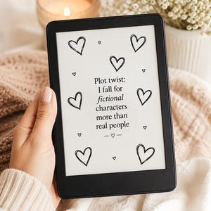 Può includere: Un e-reader nero che mostra il testo Plot twist: I fall for fictional characters more than real people circondato da diversi cuori disegnati a mano su uno schermo bianco. Il dispositivo ha una cornice nera sottile e uno schermo rettangolare.