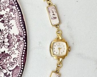 Reloj de pulsera vintage manual Caravelle Gold Vintage Broken China con casas moradas y barco
