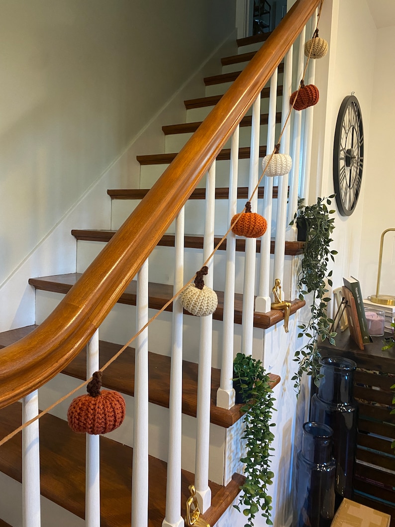 A crochet pumpkin garland on a stair railing