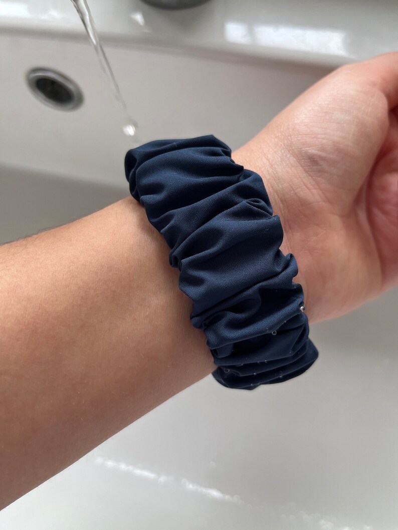 May include: A navy blue fabric watch band with a gathered, ruffled design.