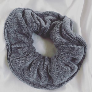 May include: A gray, soft, and textured scrunchie made of a terry cloth material.