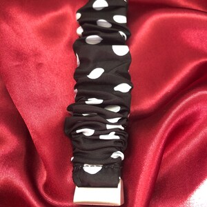 K&ouml;nnte beinhalten: Schwarzes Armband mit wei&szlig;en Punkten und einer wei&szlig;en Schnalle.