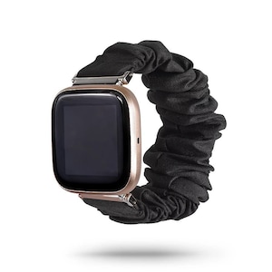 Könnte beinhalten: Ein schwarzes Scrunchie-Armband für eine Smartwatch. Das Armband besteht aus einem weichen, dehnbaren Stoff und hat einen sicheren Verschluss.