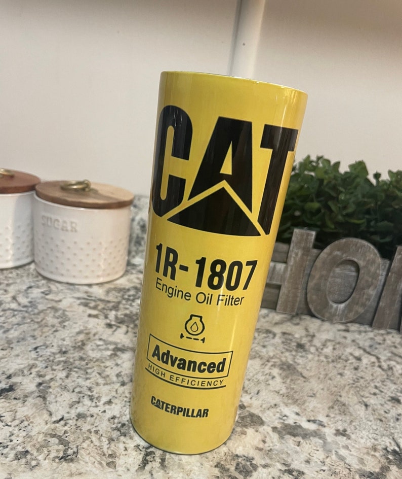 May include: Yellow and black insulated tumbler with the Caterpillar logo and the text "1R-1807 Engine Oil Filter Advanced High Efficiency Caterpillar".