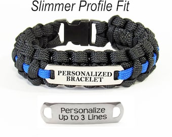 May include: Black paracord bracelet with a blue stripe and a silver metal tag that says "Personalized Bracelet". A separate silver metal tag says "Personalize Up to 3 Lines".