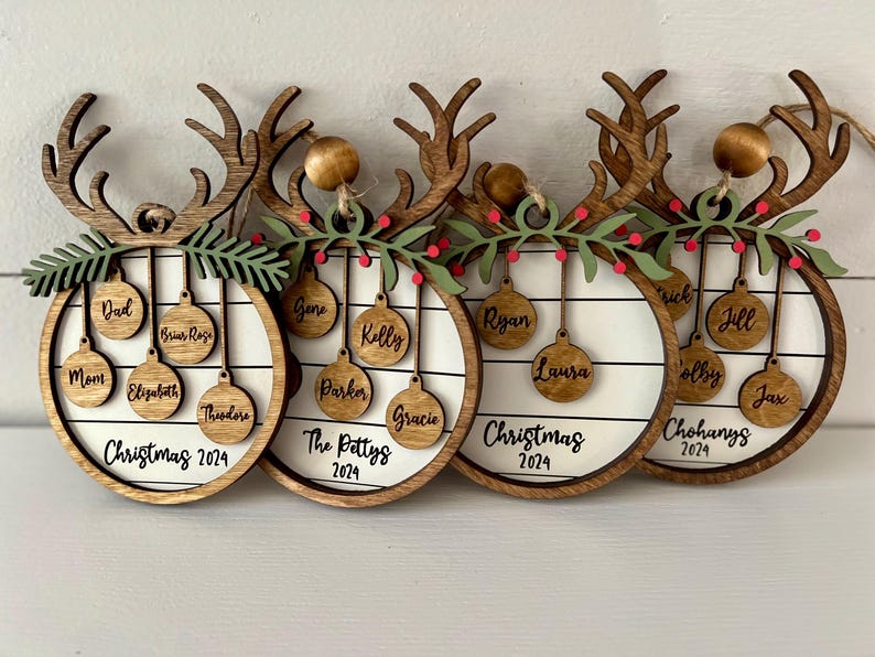May include: Four wooden reindeer ornaments with a white background and names of family members on each ornament. The ornaments are decorated with a green garland and red berries. The text on the ornaments reads "Christmas 2024", "The Pettys 2024", "Christmas 2024", and "Chohanys 2024".