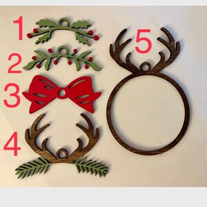 May include: Five wooden Christmas ornaments, including two green holly sprigs, a red bow, and two sets of reindeer antlers. The ornaments are numbered 1 through 5.