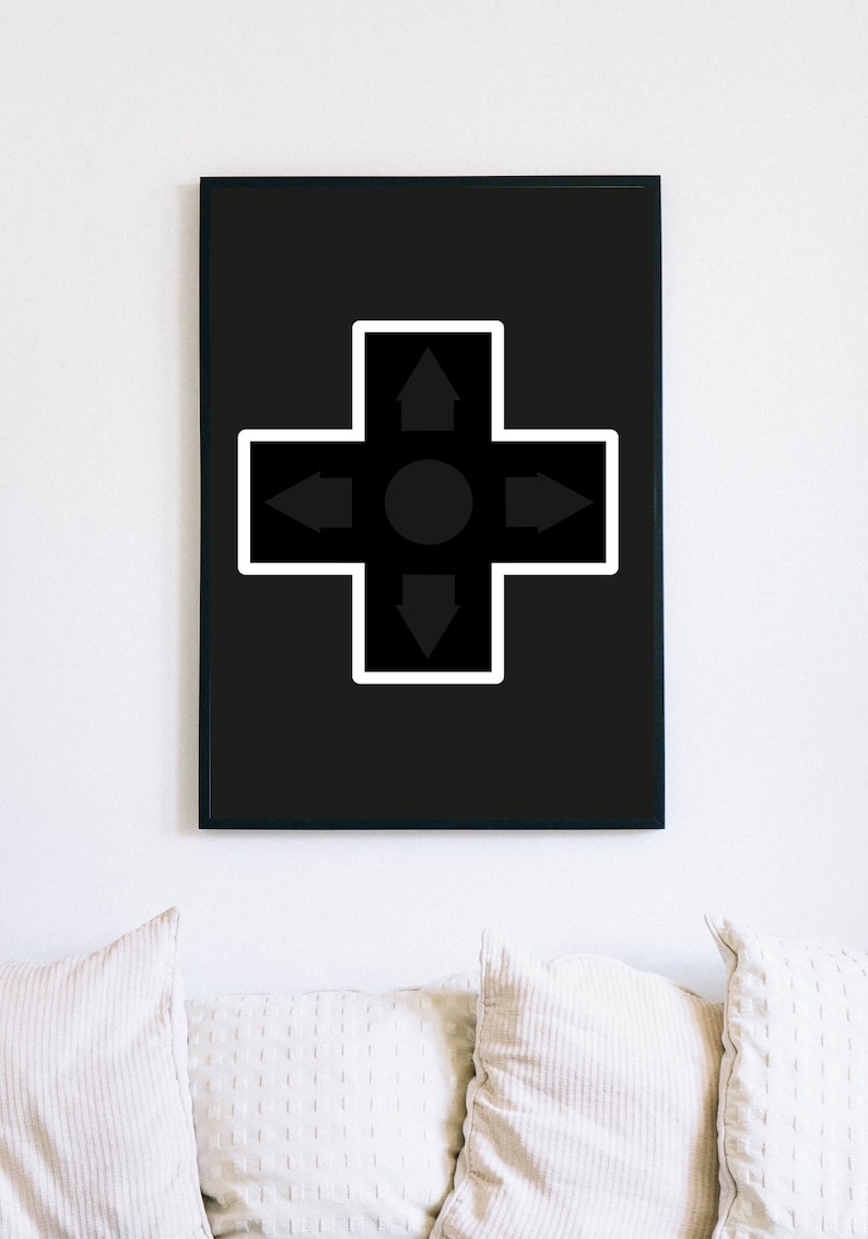 May include: Black framed wall art featuring a directional pad design. The artwork has a black background with a white-bordered cross shape. The cross contains arrows pointing up, down, left, and right, with a central circle.