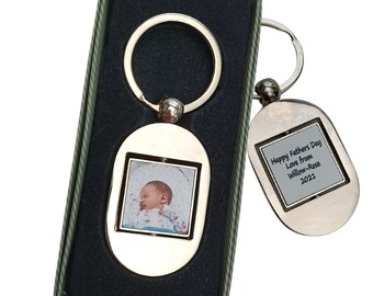 May include: Silver oval keychain with a photo of a baby and a silver oval keychain with the text "Happy Father's Day Love from Willow-Rose 2023".