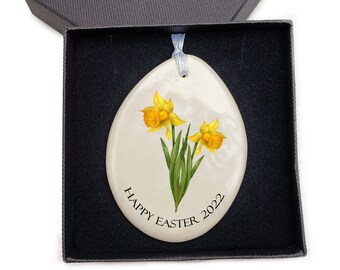 May include: White ceramic Easter egg ornament with a yellow daffodil flower design and the text "Happy Easter 2022".