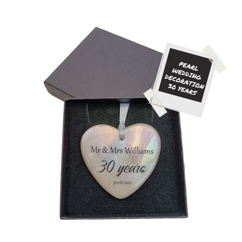 May include: A pearl white heart-shaped ceramic ornament with the text "Mr & Mrs Williams 30 years 30.06.2021" in black lettering. The ornament is in a black gift box with a white tag that reads "Pearl Wedding Decoration 30 Years".