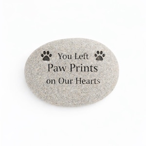 Engraved pet memorial stone with paw print design and message “You Left Paw Prints on Our Hearts” isolated on white background