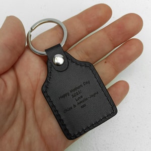 Puede incluir: Llavero de cuero negro con un anillo plateado y el texto "Happy Mother's Day 2021 Love Chloe & Amelia-Jayne xxx" grabado en &eacute;l.