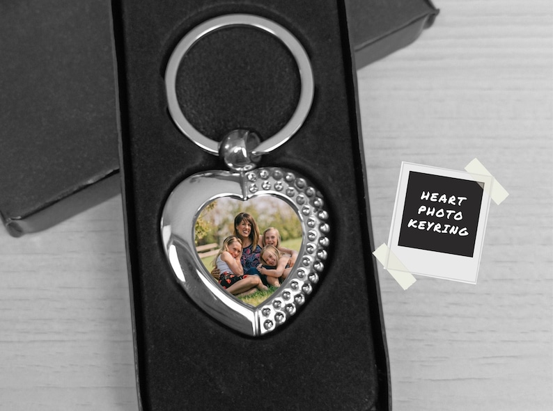Pu&ograve; includere: Portachiavi a forma di cuore argentato con una foto di una famiglia di quattro persone al centro. Il portachiavi &egrave; in una scatola nera con un'etichetta bianca che dice "HEART PHOTO KEYRING".