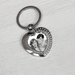 Pu&ograve; includere: Portachiavi a forma di cuore in argento con un inserto per foto che mostra due donne sorridenti. Il portachiavi ha un anello in argento per attaccarlo alle chiavi.