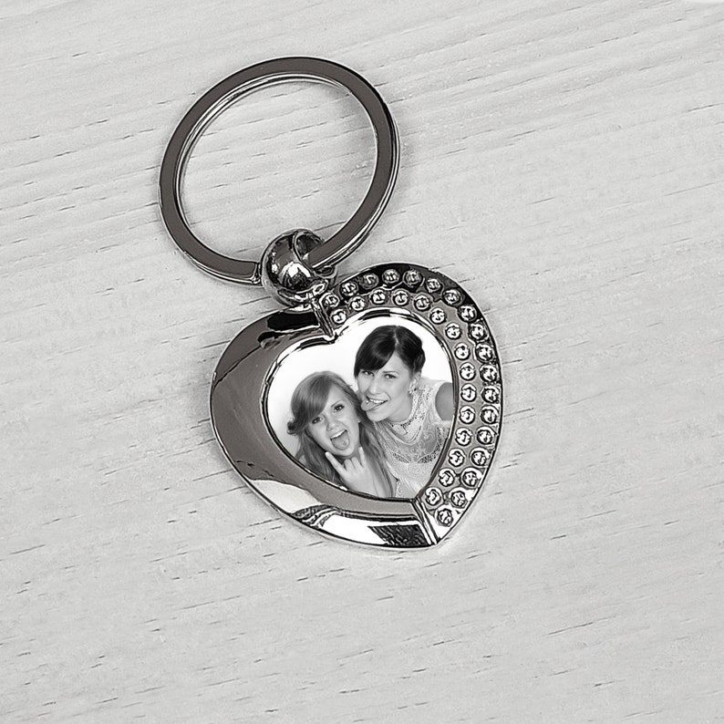 Pu&ograve; includere: Portachiavi a forma di cuore in argento con un inserto per foto che mostra due donne sorridenti. Il portachiavi ha un anello in argento per attaccarlo alle chiavi.