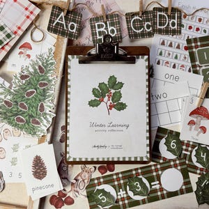 Puede incluir: Materiales educativos con temática invernal. Incluye un portapapeles con una ilustración de acebo, tarjetas con números e imágenes y papel a cuadros. El texto "Winter Learning activity collection" es visible.