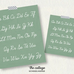 May include: A green card with white cursive letters spelling out the alphabet, "Aa Bb Cc Dd Ee Ff Gg Hh Ii Jj Kk Ll Mm Nn Oo Pp Qq Rr Ss Tt Uu Vv Ww Xx Yy Zz". The card has the text "the cottage SCHOOLHOUSE" at the bottom.