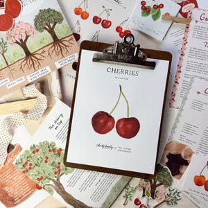 May include: A close-up of a printable card with a watercolor illustration of two red cherries. The card is titled "Cherries" and has a handwritten note at the bottom that says "Christy Ruby, the cottage homestead".