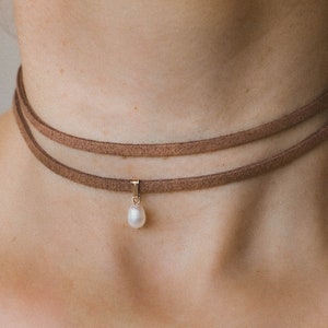 May include: A brown suede choker necklace with a single pearl pendant.