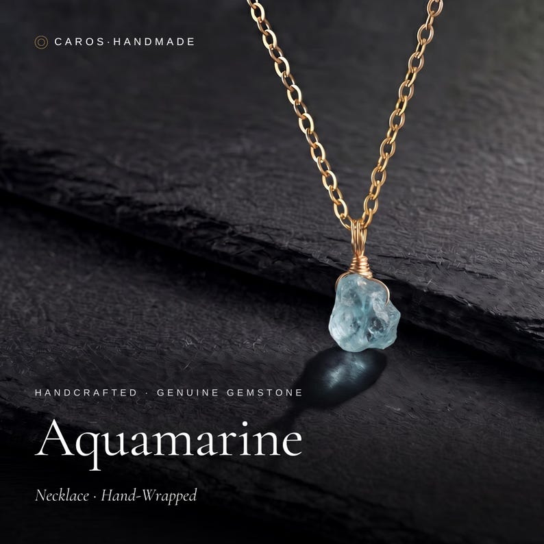 May include: A gold-toned chain necklace featuring a raw, light blue aquamarine gemstone pendant. The stone is secured with hand-wrapped gold-toned wire. Text on the image includes CAROS HANDMADE, HANDCRAFTED, GENUINE GEMSTONE, Aquamarine, and Necklace Hand-Wrapped.