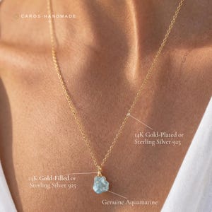 May include: A gold-colored chain necklace featuring a raw, light blue genuine aquamarine pendant. The text on the image indicates options for 14K gold-plated, 14K gold-filled, or sterling silver 925 materials for the chain and pendant setting.