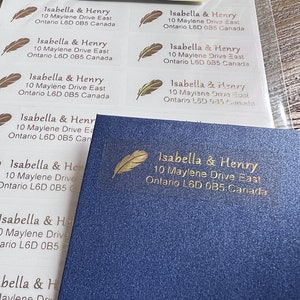 May include: A sheet of white address labels with gold foil accents. The labels feature the text "Isabella & Henry" with their address, "10 Maylene Drive East, Ontario L6D 0B5 Canada".