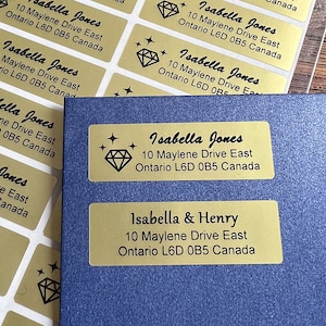 May include: Gold address labels with black text and a diamond design. The labels read "Isabella Jones" and "Isabella & Henry" with the address "10 Maylene Drive East, Ontario L6D 0B5 Canada".
