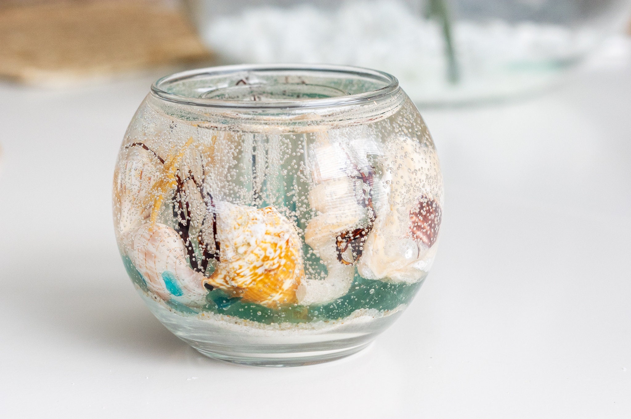 Create your own Gel candle. First decorate the bottom of the container with  colored sand, shells, glass…