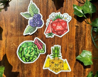May include: Four colorful stickers featuring a watermelon, a pineapple, a strawberry, and a blackberry, each shaped like a 20-sided die.