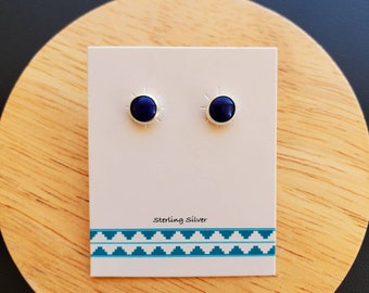 May include: A pair of sterling silver stud earrings with a blue lapis lazuli stone in each. The earrings have a sunburst design around the stone.