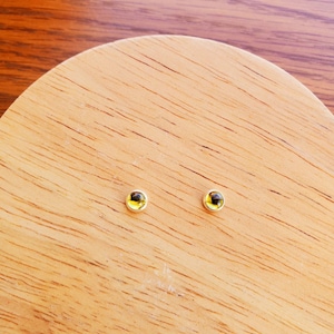 May include: A pair of gold stud earrings with small, round, yellow gemstones.