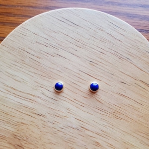 Op de afbeelding: Een paar zilveren oorbelletjes met kleine, ronde, blauwe lapis lazuli stenen.